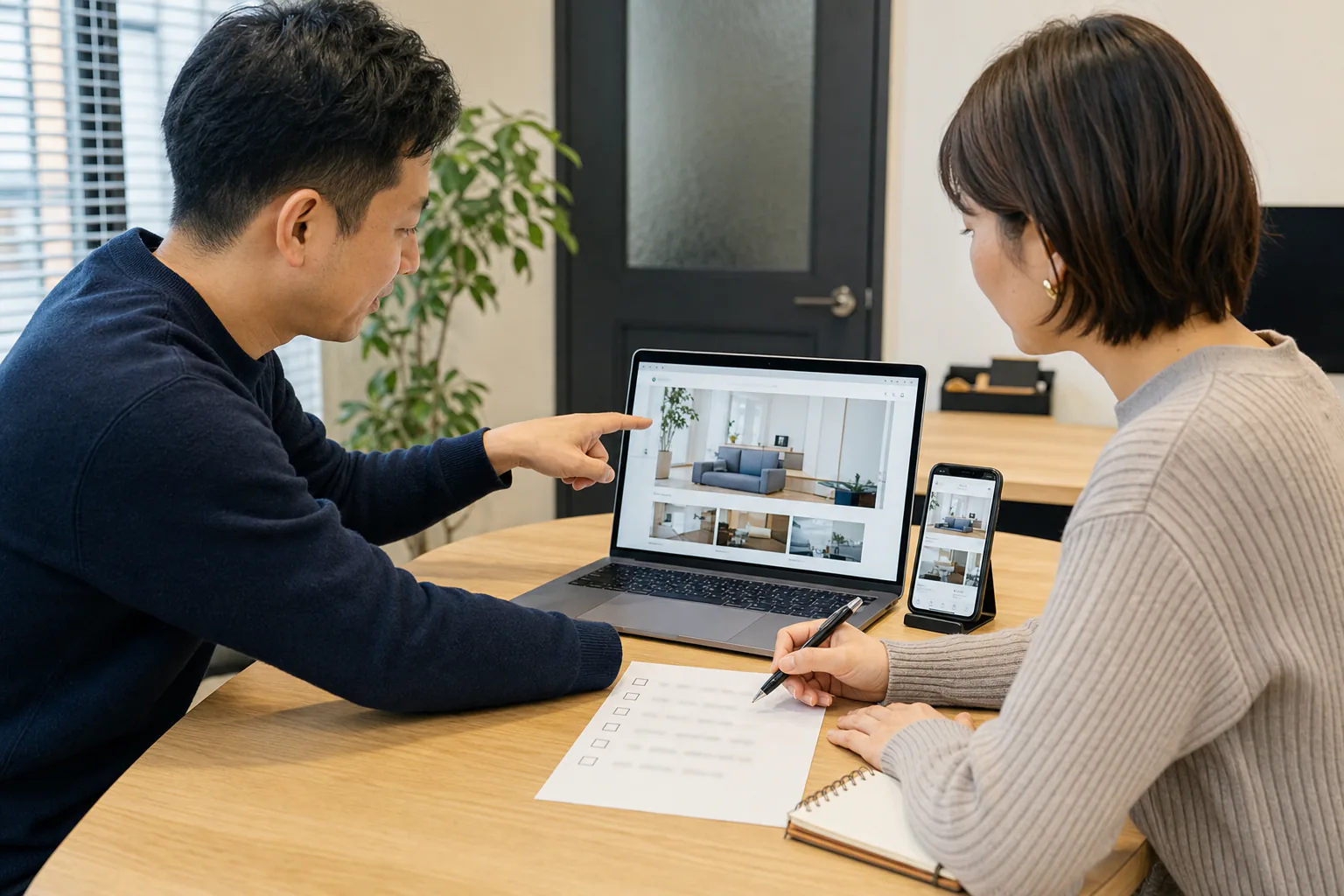 担当者とエンジニアがパソコンとスマートフォンで追加機能を確認する様子